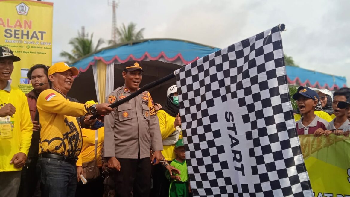 Pj Bupati Mujiyat Mengangkat Bendera Start Jalan Sehat Barito Kuala Bisa, didampingi Camat Tamban Agus Supriadi (foto:istimewa)