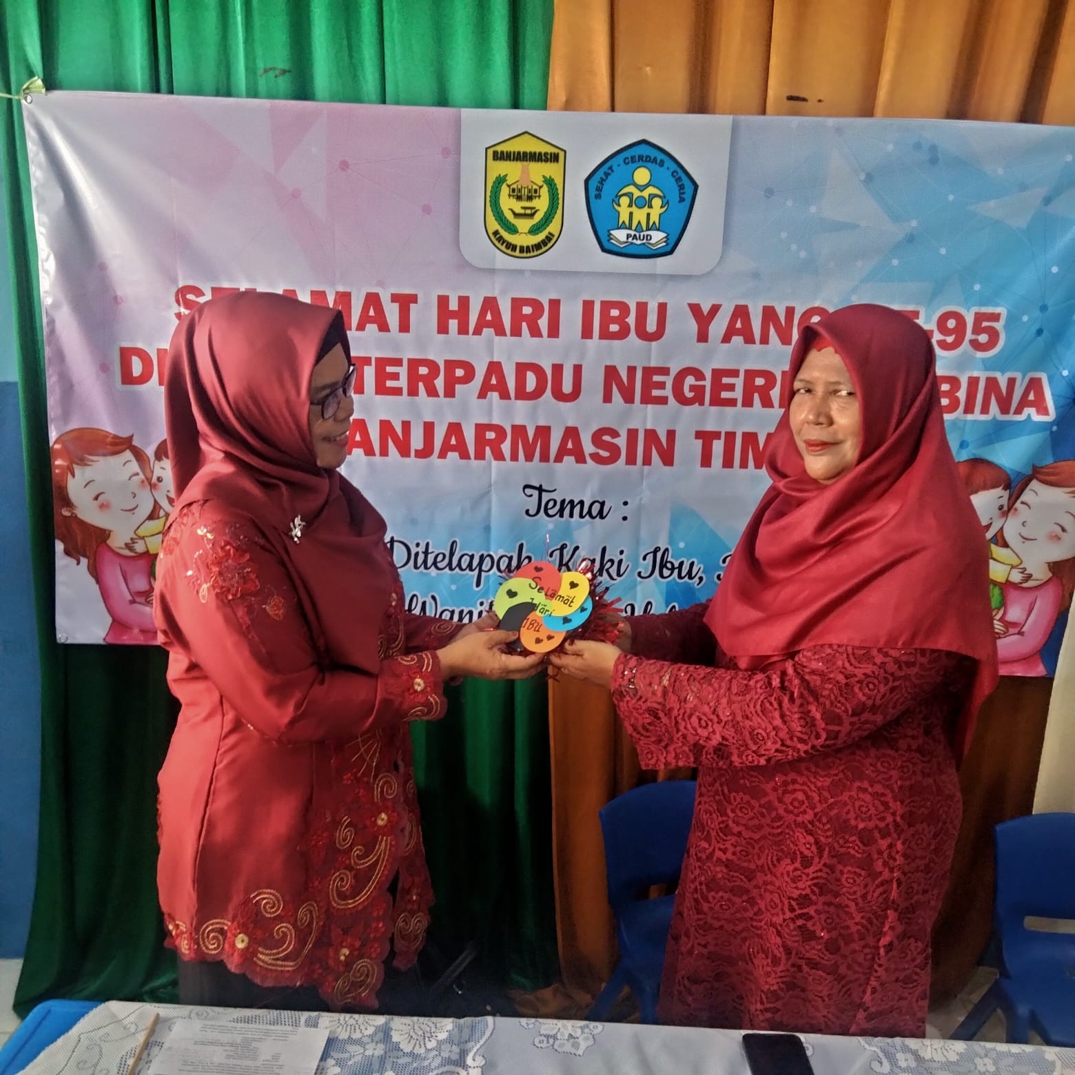 Kepala Sekolah PAUD Terpadu Negeri Pembina Kecamatan Bantim Hj Bastiah, S.pd ketika memberikan bingkisan bertuliskan Selamat Hari Ibu pada Penilik PAUD Hj Sofiah S.pd.