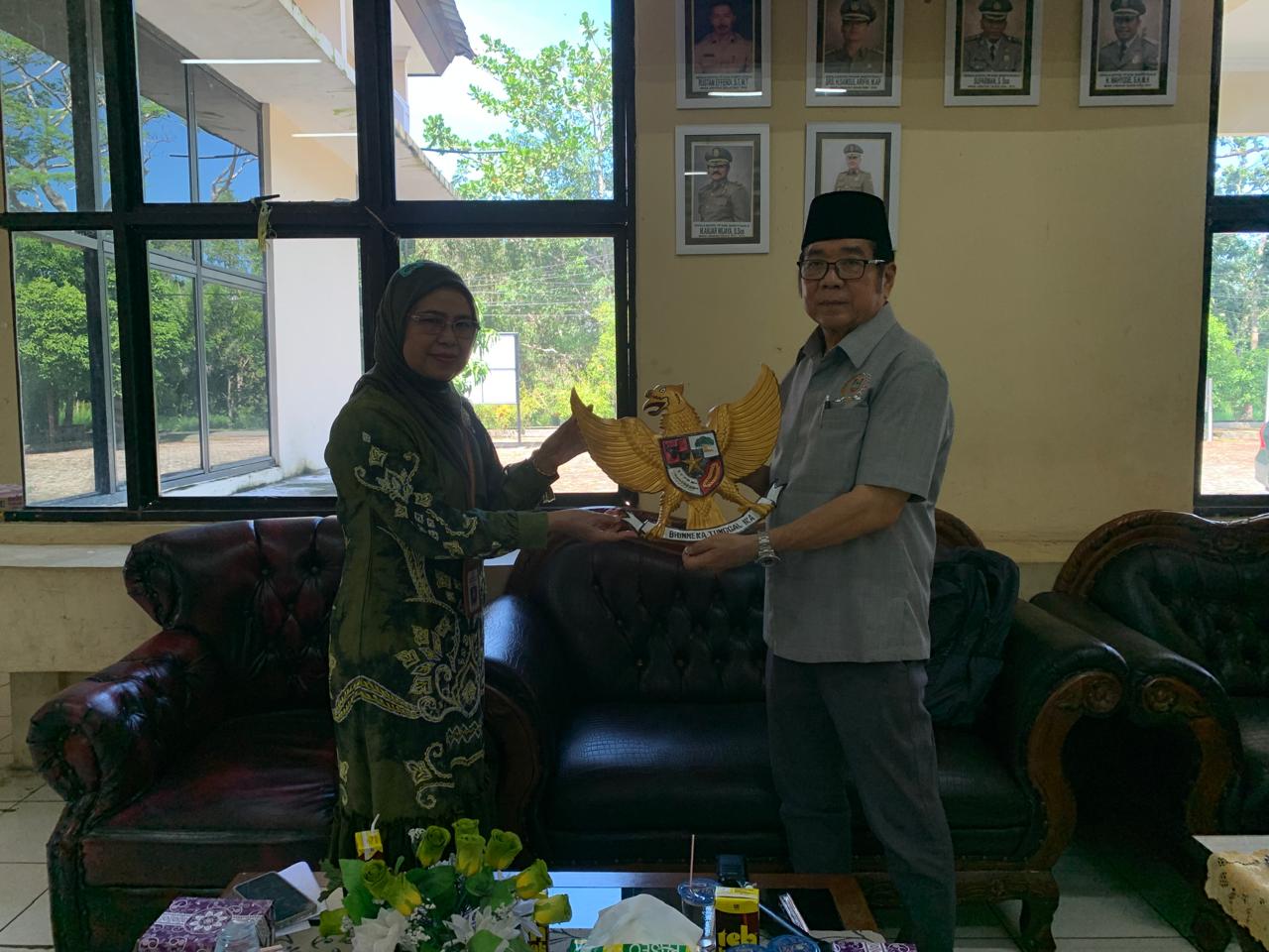 Anggota Komisi II DPRD Provinsi Kalsel Dr H Karlie Hanafi Kalianda, SH MH saat menyerahkan cindera mata berupa ukiran lambang negara Garuda Pancasila yang diterima Sekretaris  Satpol PP Kabupaten Batola Sri Wahidah,S.Ip.(foto : ist)