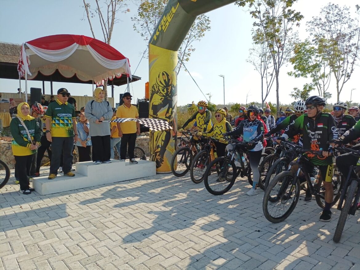 Ketua Tim Penggerak PKK Kalsel Hj. Raudatul Jannah mengibarkan bendera start Gowes Geopark 2024, Minggu (18/8) pagi di Alam Roh 24, Kiram, Kabupaten Banjar. (foto: Tolah/brt)