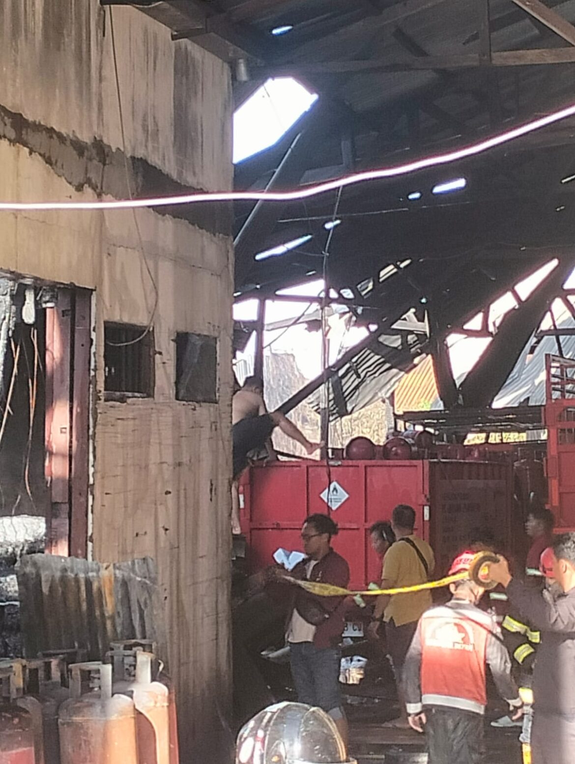 Beberapa karyawan saat membersihkan puing dan tabung gas yang terbakar di Gudang LPG PT Goutama Sinar Batuah di RK Ilir Banjarmasin, Rabu (15/10/2025) dinihari. (foto: istimewa)