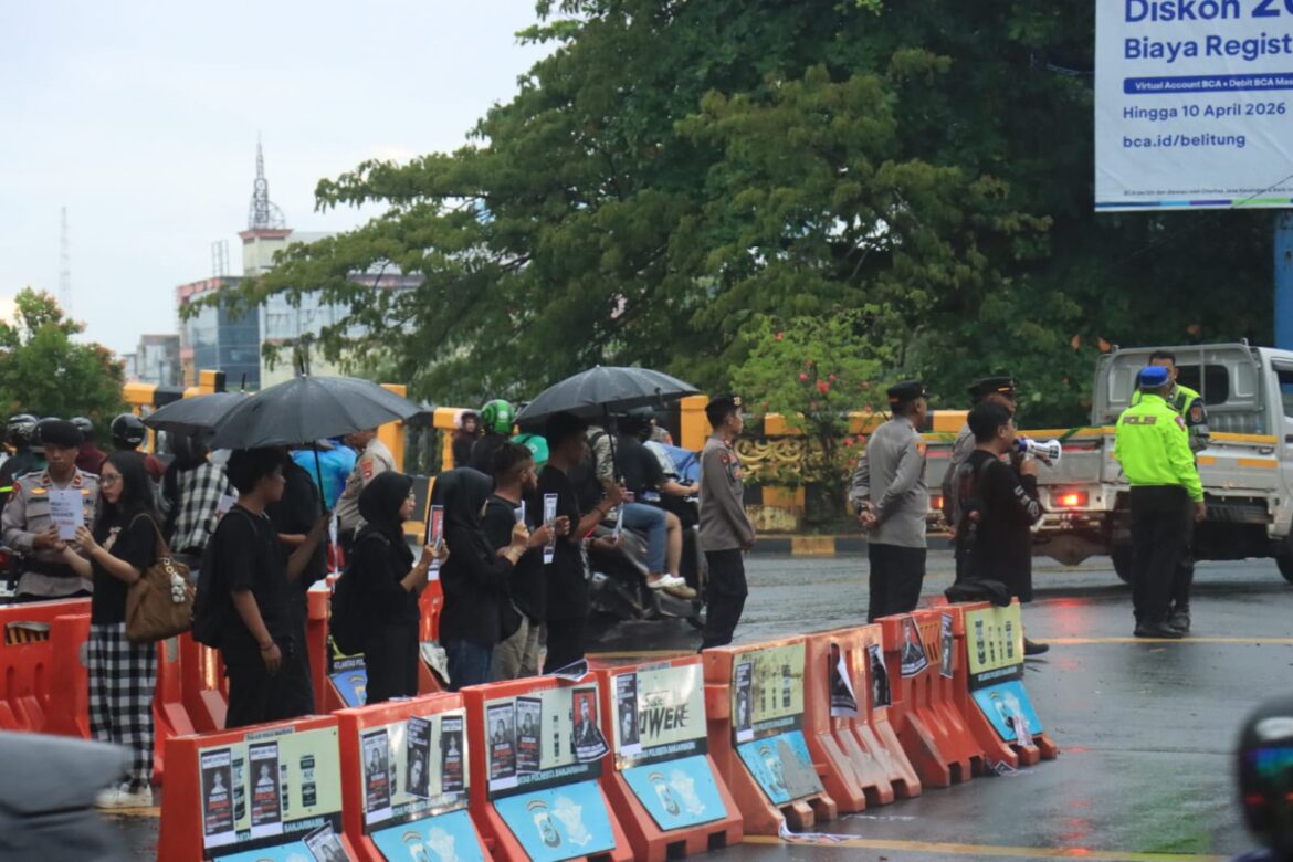 DEMO DAMAI - Meski diguyur hujan deras, personel Polresta Banjarmasin tetap melakukan pengamanan aksi Damai Kamisan di kawasan Jalan Lambung Mangkurat atau simpang empat Jembatan Merdeka, Kamis (2/4/2026) sore. (foto:istimewa)