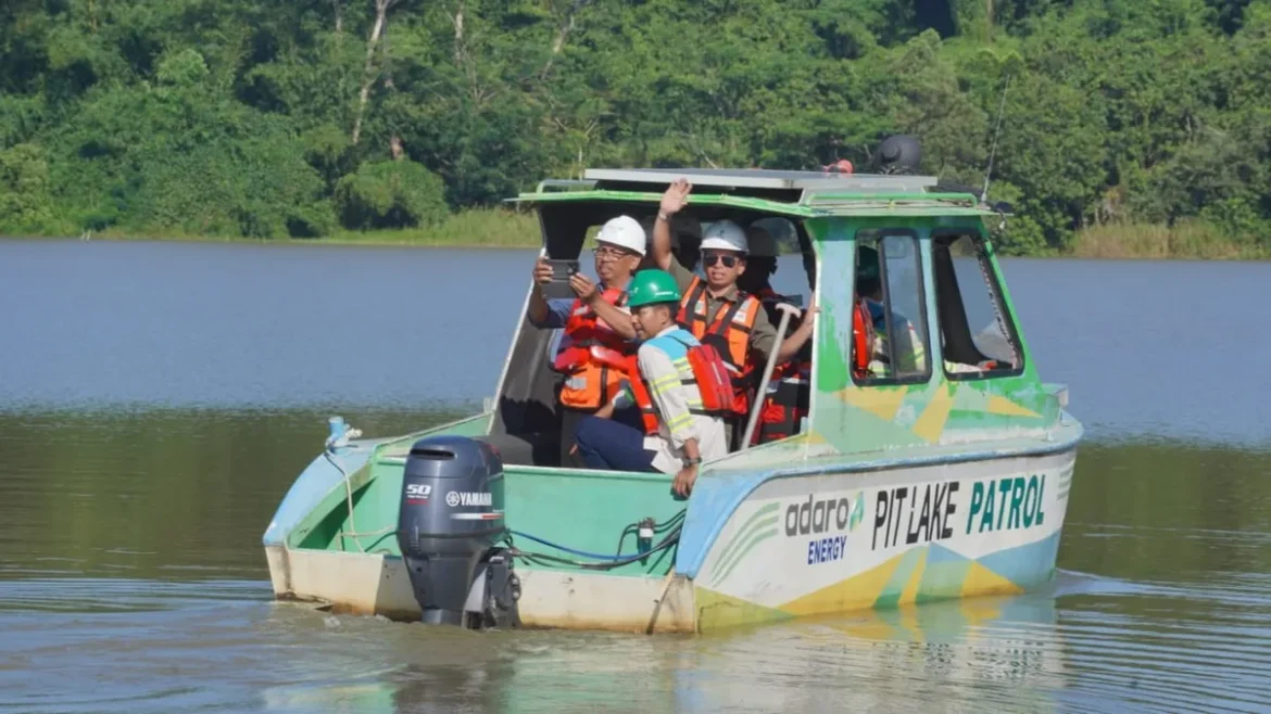 Berlatar belakang pepohonan hijau dan tebing bebatuan, tim jurnalis dari Banjarmasin dan Banjarbaru dengan helm keselamatan dan rompi pelampung berperahu motor di atas danau bekas galian tambang PT Adaro di Paringin, Kabupaten Balangan. (Foto: ist).
