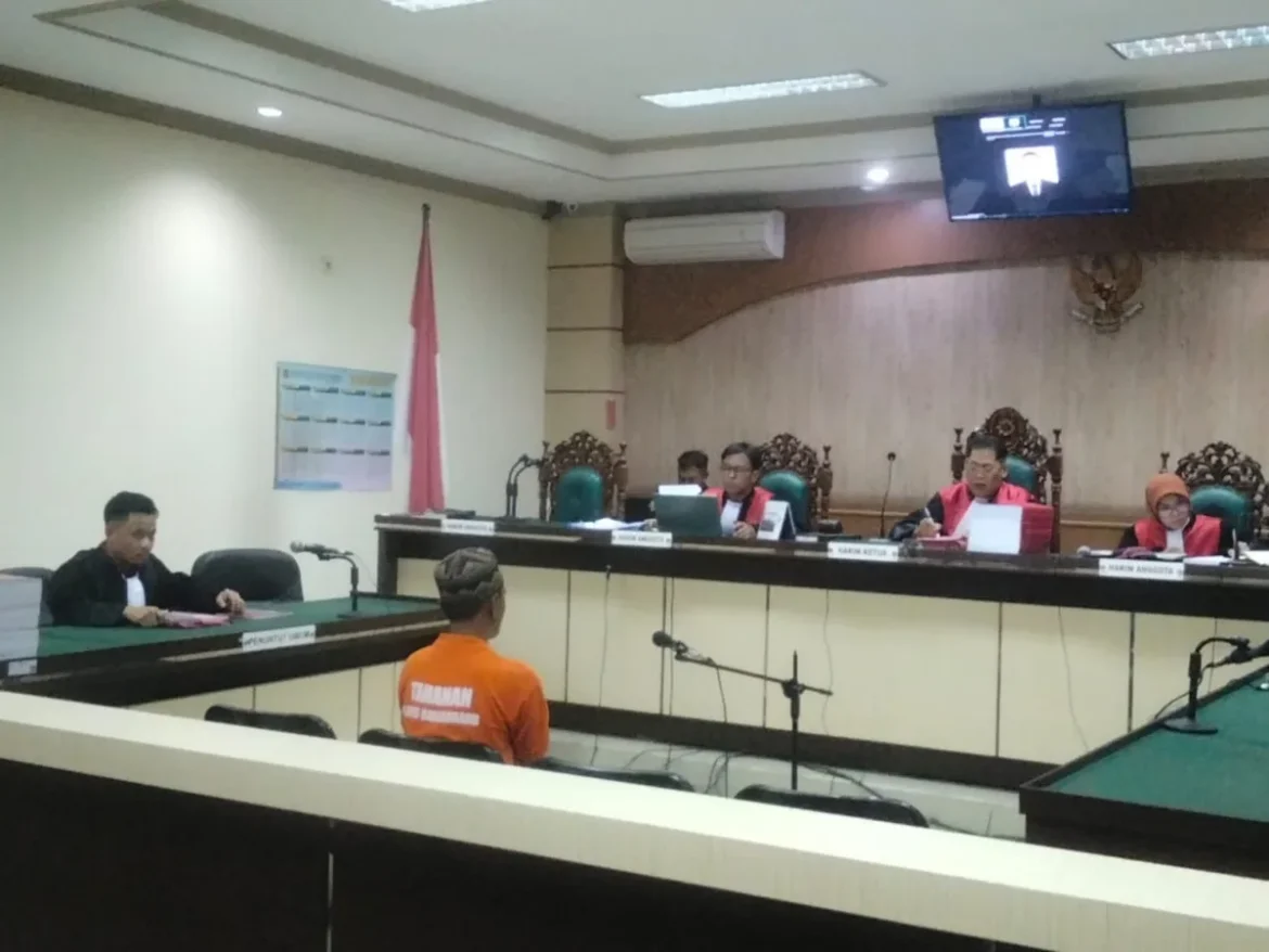 Terdakwa Helmi, Pambakal Pulantan, saat menjalani sidang perdana dengan agenda pembacaan dakwaan di Pengadilan Tipikor Banjarmasin. Jaksa menjerat terdakwa dengan pasal berlapis terkait dugaan korupsi APBDes yang merugikan negara ratusan juta rupiah.