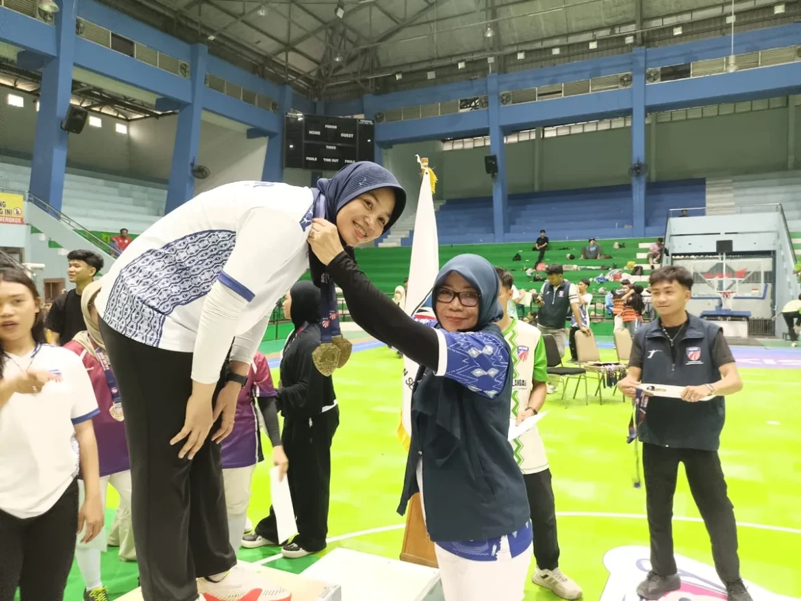 Ketua IKASI Kalsel Herita Warni mengalungkan medali kepada Wicky Putri Utami yang meraih medali emas pada Kejurprov Anggar, Kamis (3/9/2026) di GOR Hasanuddin HM Banjarmasin. (foto: Tolah/brt)