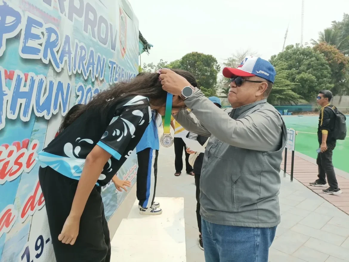Sekretaris Umum Akuatik Kalsel, Muchlis Muchtar mengalungkan medali kepada pemenang Kejurprov Renang Perairan Terbuka 2026. (foto: Tolah/brt)